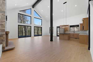 Unfurnished living room with beamed ceiling, high vaulted ceiling, light wood-style flooring, recessed lighting, and a fireplace