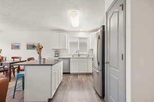 Kitchen featuring a breakfast bar, a center island, white cabinets, appliances with stainless steel finishes, and light wood-type flooring