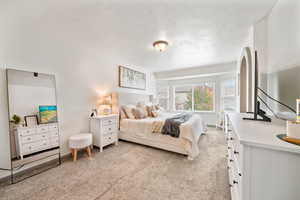 Bedroom with light carpet and a textured ceiling