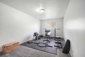 Exercise area with a textured ceiling and baseboards