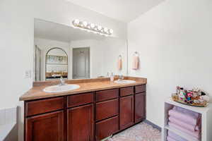 Ensuite bathroom featuring double vanity and a bathtub