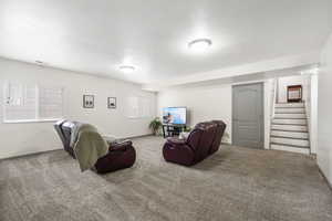 Carpeted living area with stairs, a textured ceiling, and healthy amount of natural light