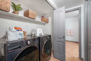 Washroom with washing machine and clothes dryer and baseboards