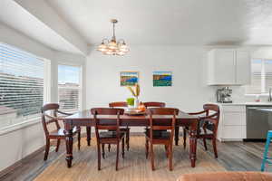 Dining space with dark wood finished floors and a chandelier