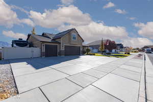 View of property exterior with a gate, concrete driveway, board and batten siding, and stone siding