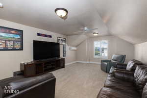 Living area with a textured ceiling, carpet, a ceiling fan, and lofted ceiling