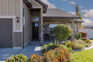 Property entrance featuring a garage, board and batten siding, covered porch, and stone siding