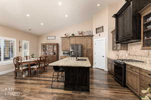 Kitchen featuring glass insert cabinets, stainless steel appliances, vaulted ceiling, light stone counters, and recessed lighting