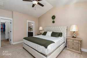 Bedroom with light colored carpet, a spacious closet, vaulted ceiling, a ceiling fan, and ensuite bath