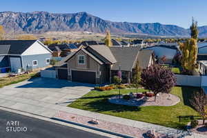 View of front of home featuring driveway, a mountain view, stone siding, and a residential view