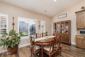 Dining area with vaulted ceiling, dark wood finished floors, and recessed lighting