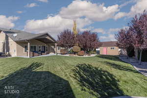 View of green lawn featuring a patio, an outbuilding, and an outdoor living space