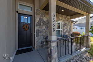 Doorway to property with a porch and stone siding