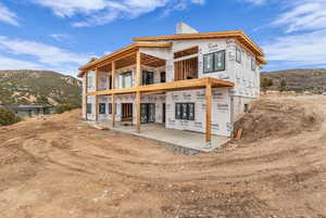 Rear view of house featuring a chimney, a balcony, and a mountain view