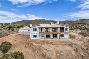 View of front of home with a chimney, a mountain view, a balcony, and a patio