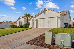 Mediterranean / spanish-style home featuring a tile roof, concrete driveway, a front yard, stucco siding, and an attached garage