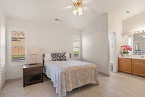 Bedroom with vaulted ceiling, connected bathroom, and a ceiling fan