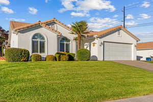 Mediterranean / spanish house with a tiled roof, stucco siding, concrete driveway, and a front yard