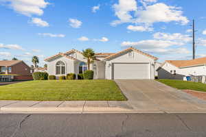 Mediterranean / spanish-style home featuring stucco siding, a front lawn, concrete driveway, an attached garage, and a tiled roof