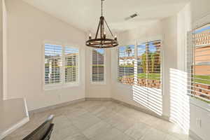 Unfurnished dining area featuring a chandelier, light tile patterned floors, and lofted ceiling