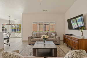 Living room with light tile patterned floors, plenty of natural light, a textured ceiling, and a chandelier