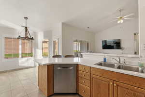 Kitchen with dishwasher, light tile patterned flooring, light countertops, open floor plan, and vaulted ceiling