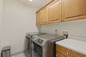 Washroom featuring separate washer and dryer and cabinet space