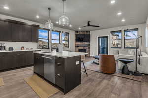 Kitchen featuring modern cabinets, open floor plan, a breakfast bar, a kitchen island with sink, and dark brown cabinetry
