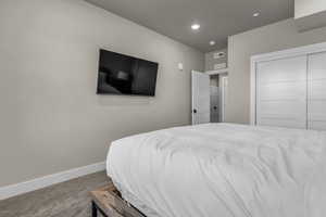 Carpeted bedroom with recessed lighting and a closet