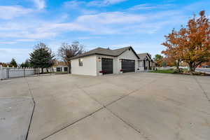 View of property exterior with concrete driveway, brick siding, an attached garage, and a gate
