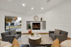 Living area featuring a decorative wall, recessed lighting, wood finished floors, a fireplace, and lofted ceiling