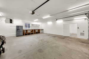 Garage featuring stainless steel refrigerator with ice dispenser, a heating unit, and a garage door opener