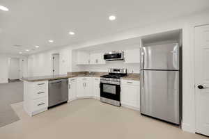 Kitchen featuring appliances with stainless steel finishes, white cabinetry, recessed lighting, light stone countertops, and a peninsula