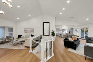 Living area featuring light wood-type flooring, lofted ceiling, recessed lighting, and a chandelier