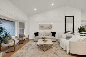 Living room with wood finished floors, vaulted ceiling, recessed lighting, and a decorative wall