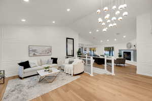 Living area featuring a high end fireplace, light wood finished floors, recessed lighting, a chandelier, and a decorative wall