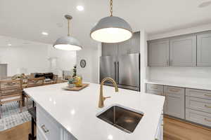 Kitchen featuring gray cabinets, high end refrigerator, light wood-style floors, light stone countertops, and recessed lighting