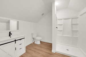 Full bath featuring vaulted ceiling, a shower stall, a textured ceiling, light wood-type flooring, and vanity