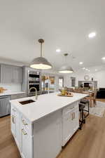 Kitchen with light wood finished floors, a large island, a kitchen breakfast bar, hanging light fixtures, and recessed lighting