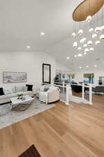 Living room featuring light wood-style floors, vaulted ceiling, a chandelier, and recessed lighting