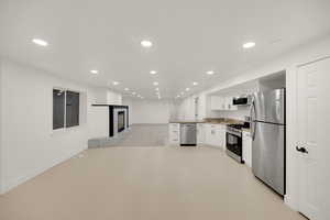 Kitchen featuring a peninsula, open floor plan, white cabinetry, appliances with stainless steel finishes, and recessed lighting