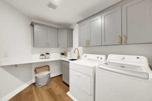 Laundry area with light wood-type flooring, independent washer and dryer, and cabinet space