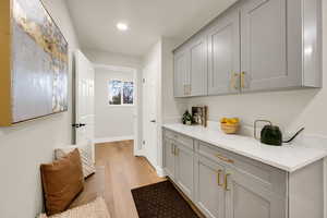Bar featuring gray cabinetry, light wood-style floors, light stone countertops, and recessed lighting