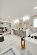 Bathroom with a freestanding bath, light marble finish floors, double vanity, recessed lighting, and ensuite bath