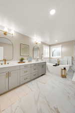 Bathroom with light marble finish floors, a soaking tub, double vanity, a textured ceiling, and recessed lighting