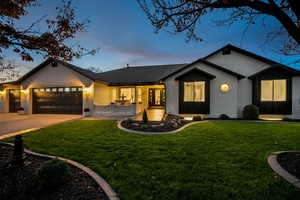 View of front of property featuring a front yard, a garage, driveway, and brick siding