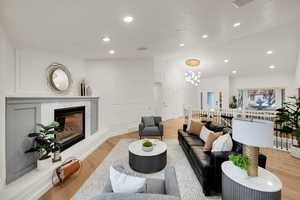 Living area featuring lofted ceiling, light wood-style floors, a premium fireplace, recessed lighting, and a chandelier