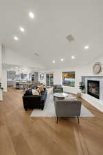 Living area featuring a premium fireplace, recessed lighting, light wood-style floors, and lofted ceiling