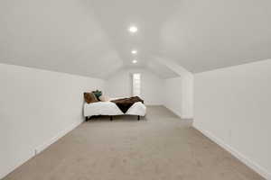 Bedroom featuring light colored carpet, lofted ceiling, and recessed lighting