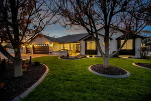 View of front facade with a yard, brick siding, a garage, and driveway